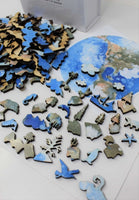 Earth wooden puzzle by Bewilderness, close-up of several whimsy pieces of flora, fauna, and a pirate ship