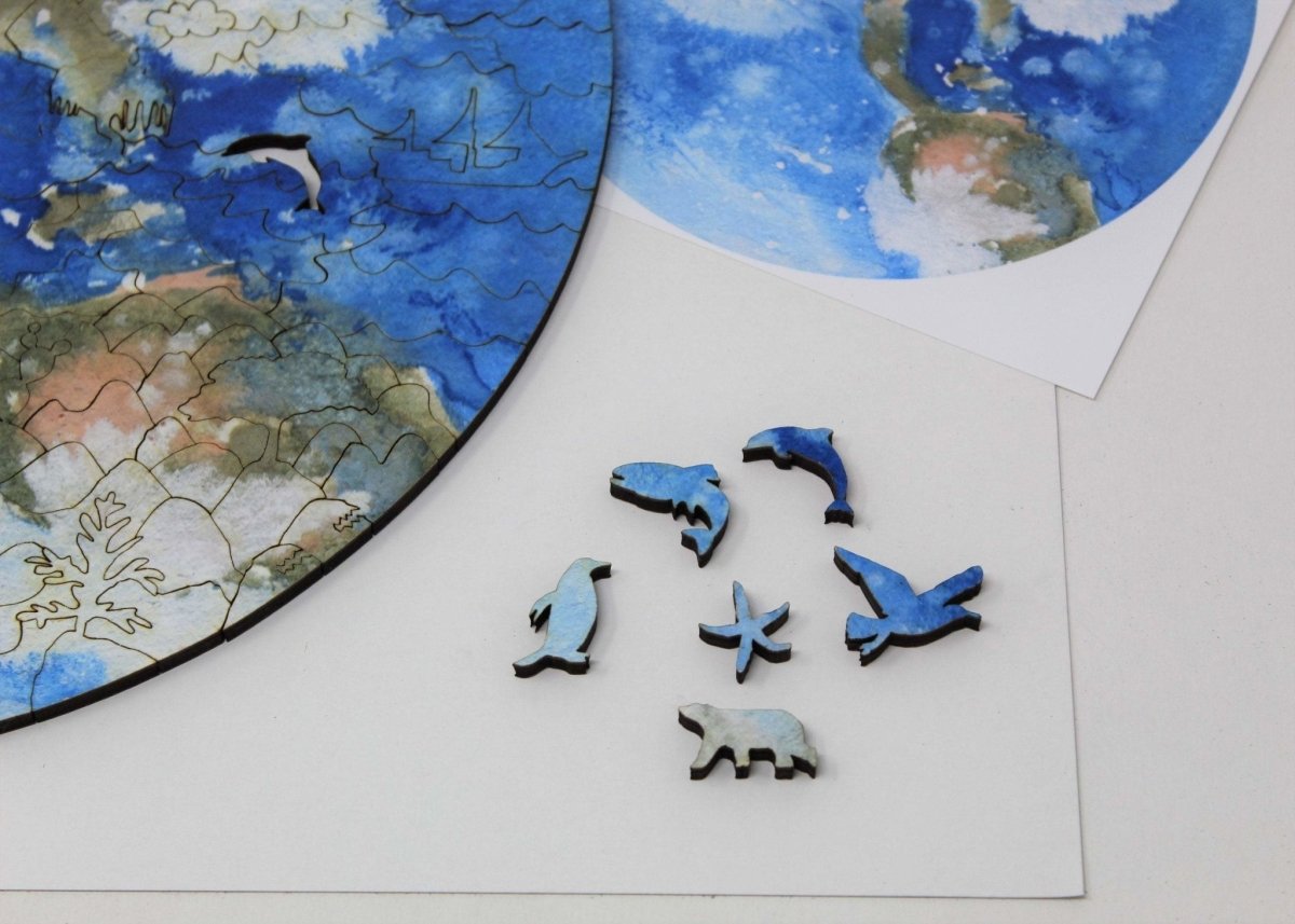 Earth wooden puzzle by Bewilderness, closeup of a few pieces: Dolphin, penguin, starfish, trout, seagull, and polar bear